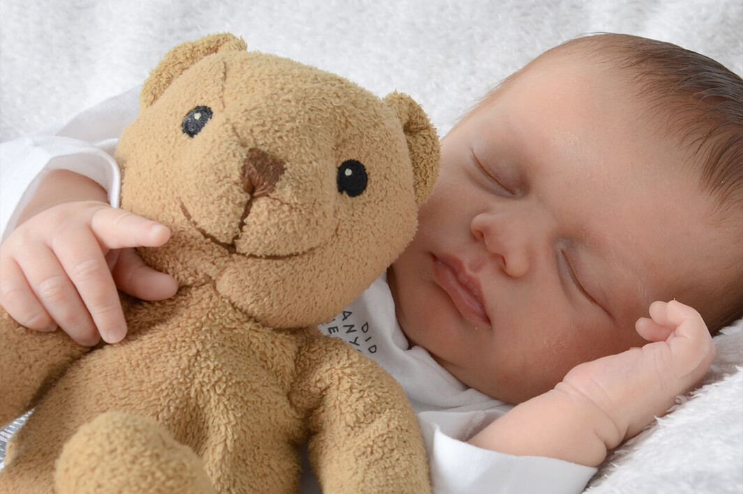 Schlafendes Baby mit Teddybär im Arm.